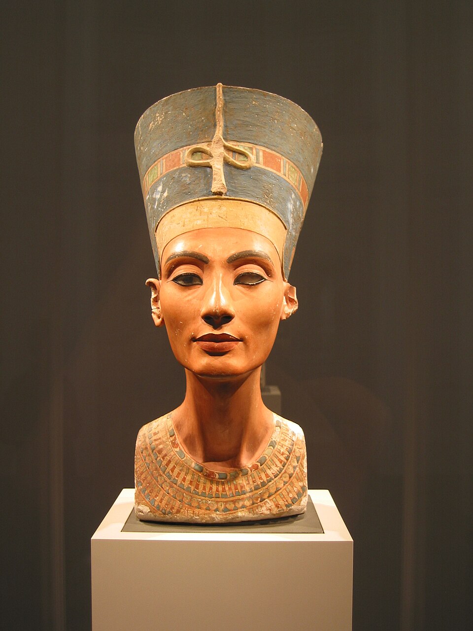 Front view of the painted limestone bust of Nefertiti displayed in a museum