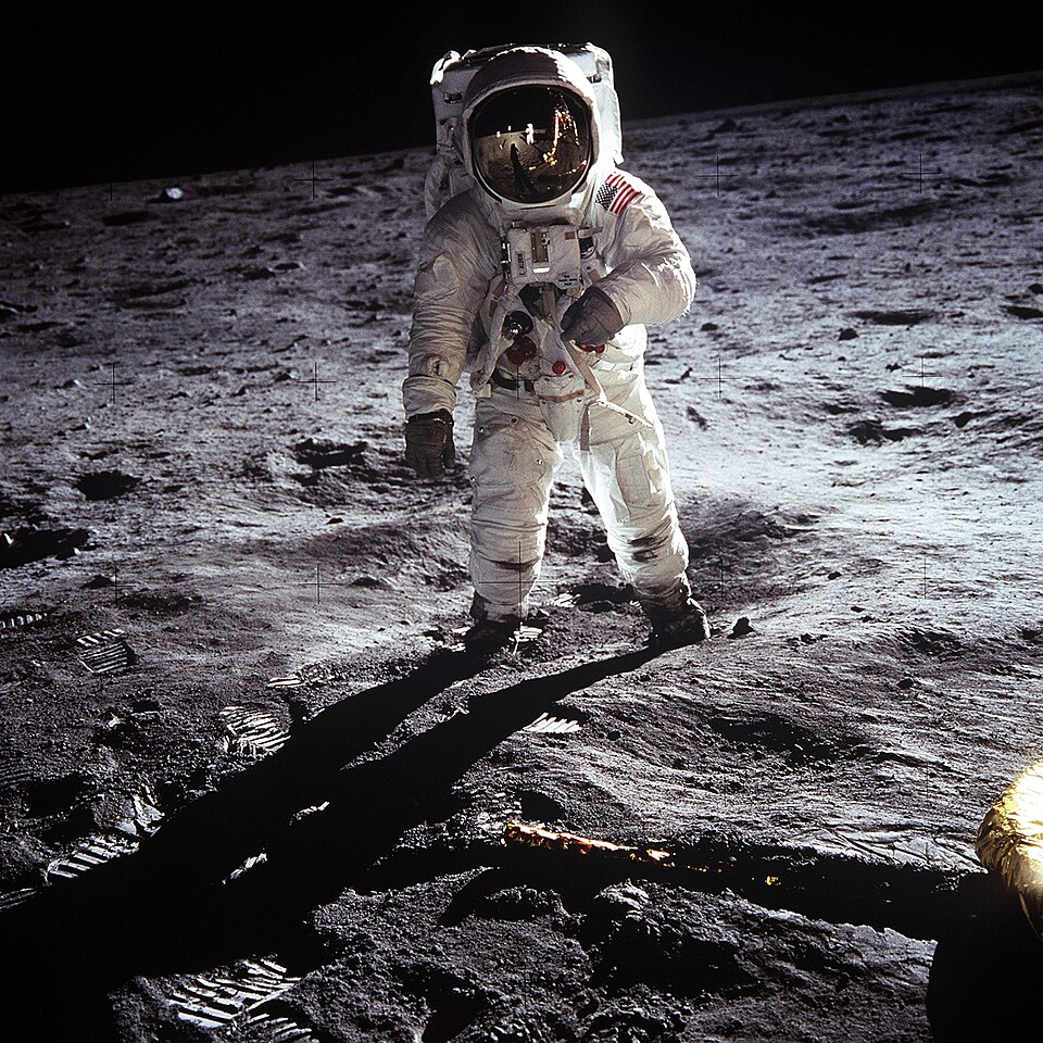 Apollo 11 astronaut Buzz Aldrin walking on the lunar surface beside a leg of the lunar module.
